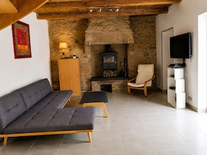 Ein gemütliches Wohnzimmer mit einer Couch, einem Sessel, einem Fernseher, einem Kamin und einer Steinwand.
