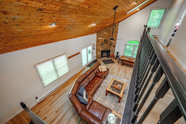 Ein Loft-Wohnbereich mit Holzboden, einem braunen Ledersofa, einem Kamin und einer Treppe.