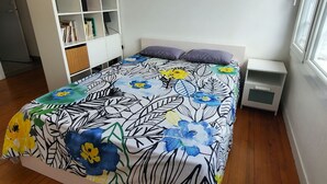 Un dormitori amb un llit, un armari blanc, una taula de nit i una finestra.