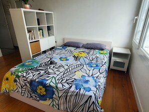 Ein Schlafzimmer mit einem Bett, einem weißen Kleiderschrank, einem Nachttisch und einem Fenster.