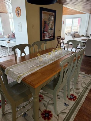 Un coin repas avec une table en bois, une nappe blanche et des vases décorés de motifs floraux.