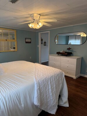 Un dormitorio con cama, cómoda, espejo y ventilador de techo.