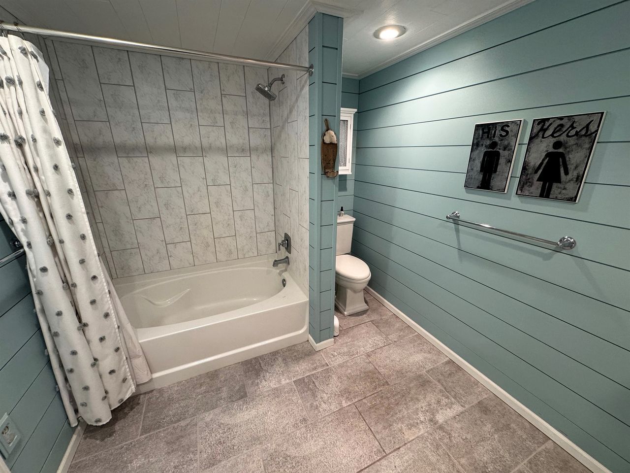 Une salle de bain avec une baignoire, des toilettes et un rideau de douche.