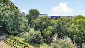 Un área ajardinada con árboles y una masa de agua, rodeada de edificios.