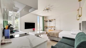 Una habitación de hotel moderna con cocina, una cama, un sofá y un televisor.
