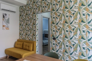 A room with a yellow sofa, a wooden table, and a patterned wallpaper. - Allegra House (Alba Adriatica)