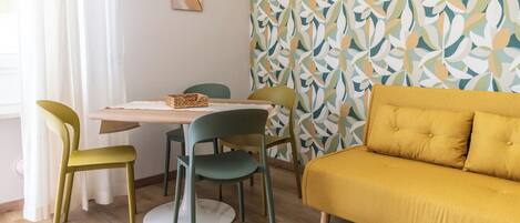 A dining area with a table, chairs, and a sofa.