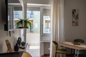 Ein modernes Wohnzimmer mit Essbereich, einem großen Fenster und Blick auf ein Gebäude.