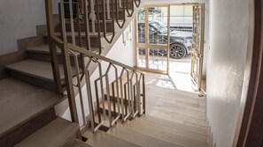 Eine Holzhandlauf-Treppe führt zu einer Tür mit Glasfenster.