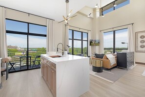 Ein geräumiger Wohnbereich mit großem Fenster, Kücheninsel und Balkon.