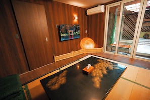 A tatami mat room with a television, a traditional Japanese lantern, and a sliding door leading to a balcony. - Exclusive Whole-House Ryokan in Sapporo | Features a Japanese Garden, Open-Air Bath, and Sauna / Accommodates up to 16 Guests: 10-minute walk from Subway 27-jo Station (札幌市)