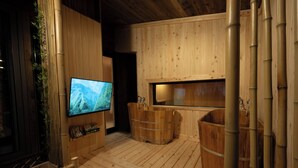 Interior em madeira com televisão, banheiras de madeira e detalhes em bambu.