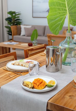 Une table à manger avec une assiette de nourriture, un verre et un récipient en métal.