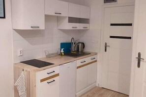 Cuina amb armaris blancs, tauleig negre, una papereta i un rentapots.