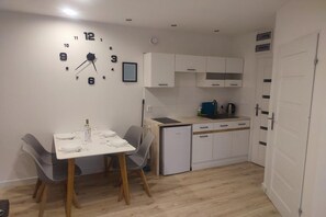 Una cucina compatta con mobili bianchi, forno integrato e tavolo con sedie.