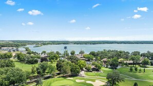 Un parcours de golf avec vue sur un lac, une tour à eau et un espace de stationnement.