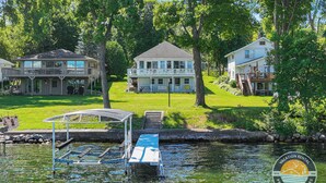 Une propriété au bord du lac, dotée d’un quai, d’un abri pour bateaux et d’une maison avec balcon.