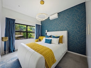 Een slaapkamer met een bed, gordijnen, een raam en een airconditioning.