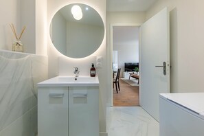 Ein modernes Badezimmer mit großem Spiegel, Waschbecken in Weiß und Toilette.