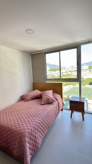 A bedroom with a large window, a bed, and a nightstand. - Modern Premium Apartment on the Golden Mile, 11th Floor (ibague)