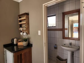Een badkamer met een houten plank, een wastafel, een spiegel en een raam.