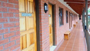 Un pasillo con paredes de ladrillo, puertas de madera y suelo de baldosas.