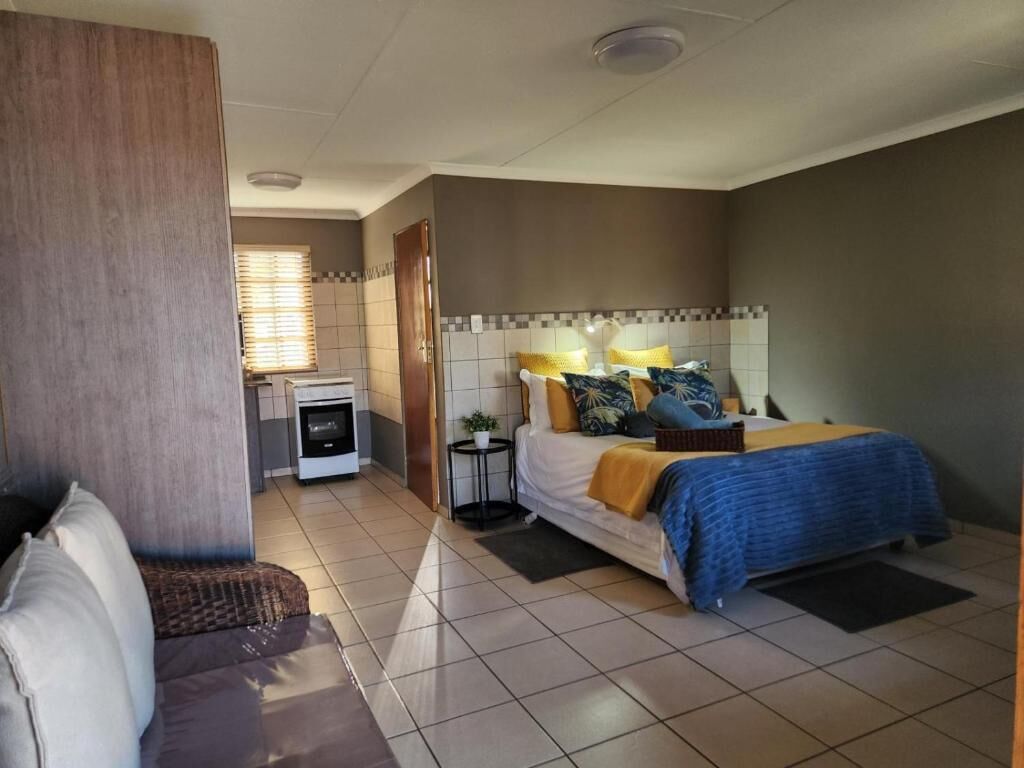 A bedroom with a bed, bedside table, and a small kitchenette.