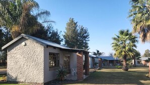 Un edificio de un piso con techo plano, un pequeño porche y un patio cubierto de césped.