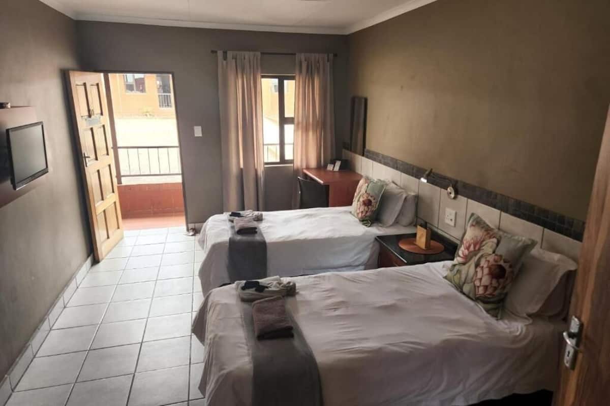 Habitación de hotel con dos camas, un escritorio, un televisor y vistas al exterior.