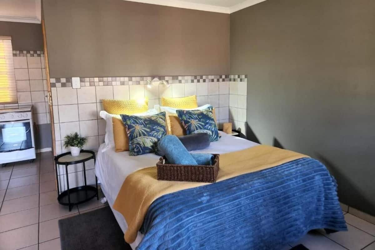 Habitación de hotel con cama, una mesita auxiliar, una planta en maceta y vistas a la cocina.