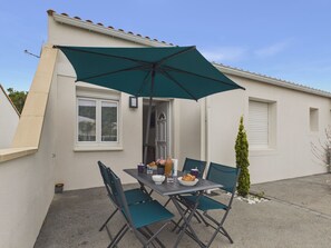Eine Terrasse mit Tisch, Stühlen und einem großen Sonnenschirm.