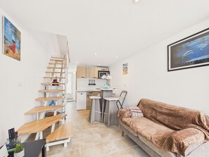 Ein kompakter Wohnraum mit Küche, Treppe, Sofa und Essbereich.