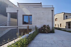 Un bâtiment moderne avec une façade en béton, une fenêtre et un petit jardin agrémenté de fleurs.
