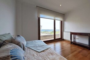 A bedroom with a bed, a window with a view, and a wooden floor. - Disconnect in Galicia: A Journey to the Sea (Pontevedra)