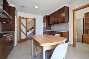 Uma cozinha moderna com armários de madeira, bancada de granito e área de refeições com mesa e cadeiras de madeira.