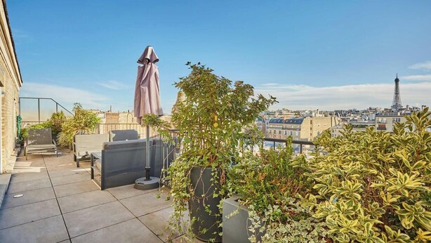 Terrassa al terrat amb seients exteriors, una estàtua i vista a la Torre Eiffel.