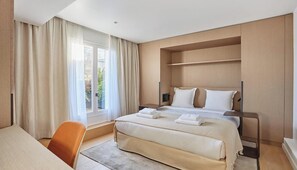 A modern hotel room with a large bed, a desk, and a chair. - A RARE COMBINATION OF LUXURY, COMFORT & PANORAMIC VIEWS OF THE EIFFEL TOWER (Paris)