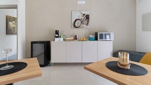 Una cocina moderna con un refrigerador, microondas y una cafetera sobre el mostrador.