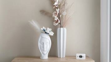 Un vase blanc contenant des fleurs séchées et un autre vase blanc avec une composition florale, le tout posé sur une surface en bois.