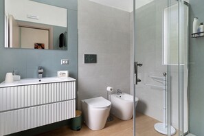 Un baño moderno con inodoro, bidé y cabina de ducha de vidrio.