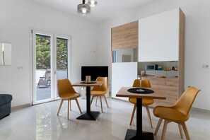 Un comedor moderno con un ventanal que da a un espacio exterior, un televisor de pantalla plana y un armario de madera.