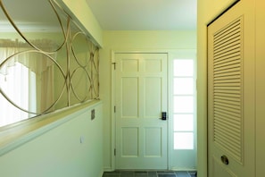 A hallway with a white door, a window with curtains, and a wall-mounted vent. - Comfortable 4-Bedroom Home in Mt Morris (Mount Morris)