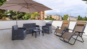 An outdoor patio with wicker furniture, a table with glasses, and a large umbrella.