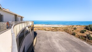 A coastal road leading to a beach with a white building on the left. - L’Échappée Océane - 100 m de la plage (Soulac-sur-Mer)