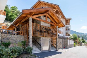 Ein Gebäude mit einer Holzfassade, Steinsäulen und einem Schild mit der Aufschrift 'Chalet Malone & Viggio'.