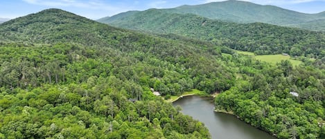 Eine bewaldete Landschaft mit einem Fluss, Hügeln und einem kleinen Gebäude.