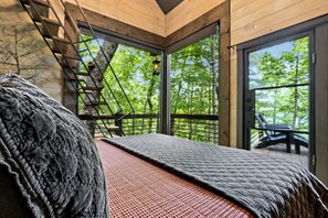 Una habitación con cama, escalera y balcón con una silla.