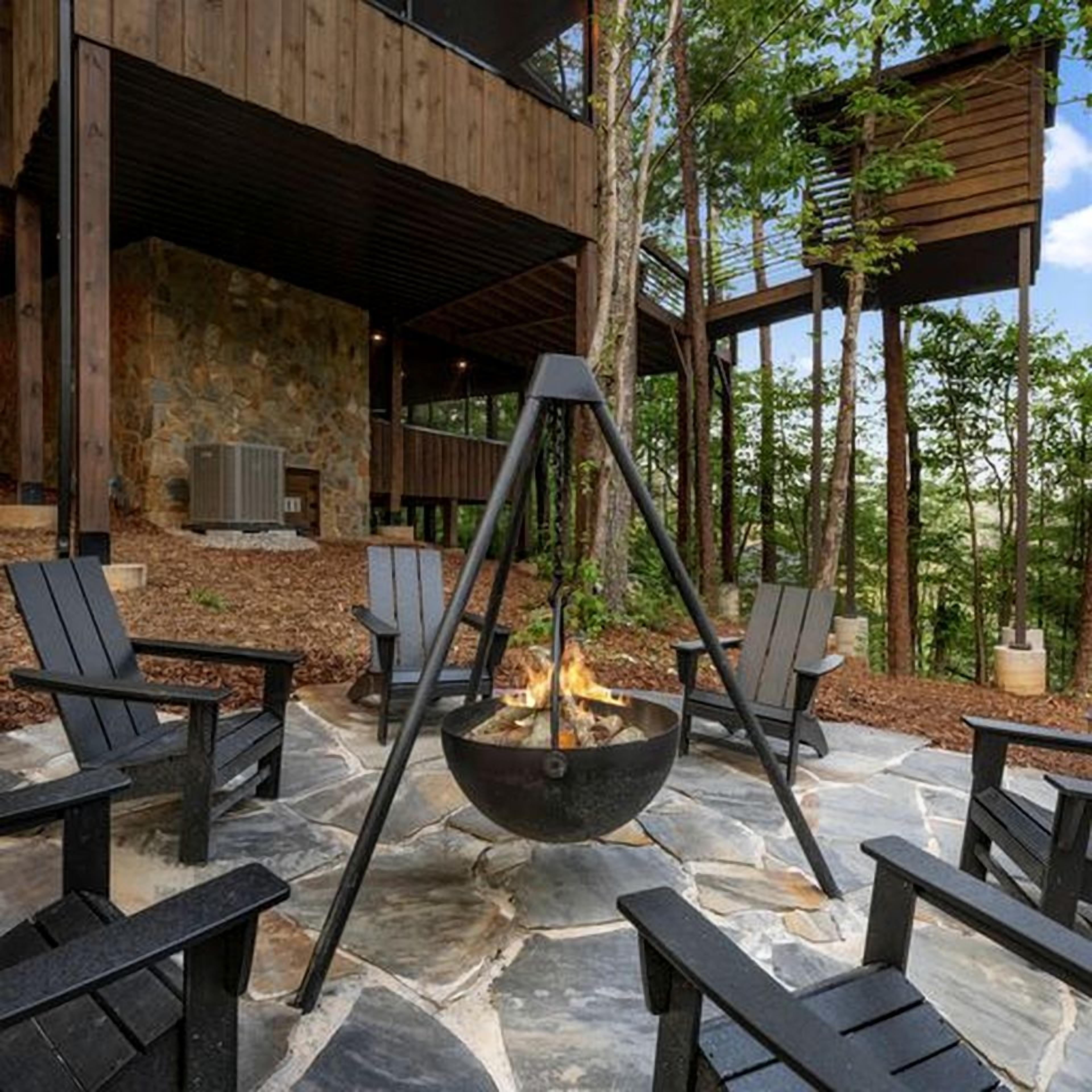 A stone patio with a fire pit and Adirondack chairs.