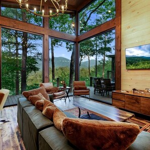 Un interior moderno con un sofá grande, una zona de comedor y un televisor.