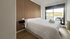 A modern hotel room with a large bed, a wooden slat wall, a window with a balcony view, and a ceiling light. - Desconectaengalicia Mar de Silgar 2, 600 m from Silgar Beach (Pontevedra)